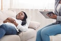 Depressed young black woman lying on couch during psychotherapy session Royalty Free Stock Photo