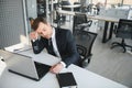 Depressed young businessman holding head in hands, has problem, a laptop on the desk. A guy made a mistake in a work Royalty Free Stock Photo