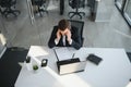 Depressed young businessman holding head in hands, has problem, a laptop on the desk. A guy made a mistake in a work Royalty Free Stock Photo