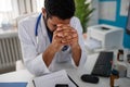 Depressed young male doctor with headache sitting in his office Royalty Free Stock Photo