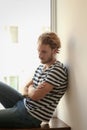 Depressed young man near window at home Royalty Free Stock Photo
