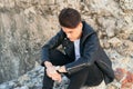 Depressed young man sitting outdoors looking down, unhappy about the breakup Royalty Free Stock Photo