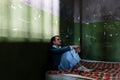 Depressed young man sitting on a mattress in a dark prison cell during custody Royalty Free Stock Photo