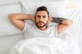 Depressed young man unable to sleep, lying in bed, looking up and contemplating, top view Royalty Free Stock Photo