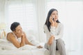 Depressed young woman sitting on bed calling on phone having problems with boyfriend