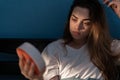 Depressed young woman sitting in bed looking on clock cannot sleep, suffering from insomnia. Sleep apnea, insomnia or Royalty Free Stock Photo