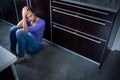 Depressed young woman, sitting on the kitchen floor Royalty Free Stock Photo