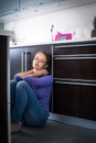 Depressed young woman, sitting on the kitchen floor Royalty Free Stock Photo