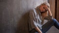 Depressing girl. sits on the floor. Depression and chronic fatigue. Young beautiful blonde in gray sweater and jeans