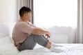 Lonely korean man sitting on bed, looking through window Royalty Free Stock Photo