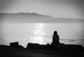 Depression. black and white photo of melancholic alone girl sitting by the sea feeling sad and contemplating Royalty Free Stock Photo