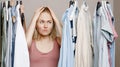 Depression a woman holds her head with her hands, standing near a closet full of clothes, facing a difficult choice of