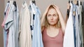 Depression a woman holds her head with her hands, standing near a closet full of clothes, facing a difficult choice of