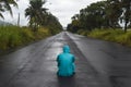 Depressive concept with lonely man in raincoat sitting on wet road under rain Royalty Free Stock Photo