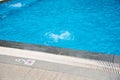 Depth market in meter, no diving sign near linear drains and marble edge of large upscale swimming pool with splash water by