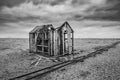 Derelict fishing hut and rails on shingle beach during stormy Wi