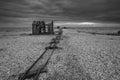 Derelict fishing hut and rails on shingle beach during stormy Wi