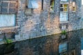 Derelict industrial reflection closeup of stone wall broken windows and doors on edge of city canal Royalty Free Stock Photo