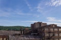 Derelict industrial warehouse with modern commercial building and forested hillside beyond Royalty Free Stock Photo