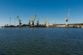 Derelict port cranes line harbor, symbolizing industrial decline. Unused loading equipment stands against clear sky Royalty Free Stock Photo