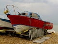 A derelict red motor boat on a beach