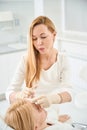 Dermatocosmetologist making microinjections inserting filler in female forehead