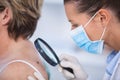 Dermatologist examining mole of female patient with magnifying glass Royalty Free Stock Photo