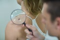 Dermatologist examining mole with magnifying glass Royalty Free Stock Photo