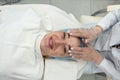 dermatologist performs a facial rejuvenation procedure with a cream in a spa center.