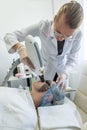 dermatologist wearing a medical mask and rubber gloves applies a mask to a client& x27;s face.