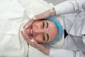 dermatologist wearing a medical mask and rubber gloves applies a mask to a client& x27;s face.