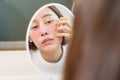 Dermatology, puberty asian young woman, girl looking into mirror, allergy presenting an allergic reaction from cosmetic, red spot Royalty Free Stock Photo