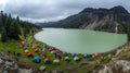 A lush, green campsite along the shores of a calm lake in a mountainous area. Royalty Free Stock Photo
