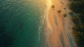 Aerial view of a serene beach at sunset, featuring golden sand and clear blue-green. Royalty Free Stock Photo