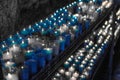 Desaturated blue image of a closeup of colorful candles burning in the tunnel of Covadonga, Cangas de Onis, Asturias, Spain. Royalty Free Stock Photo