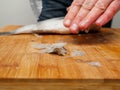 Descaling fish, Pile of scale in foreground, selective focus. Sea bream on a wooden cutting board. Fishmonger at work