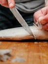 Descaling fish with sharp knife, selective focus. Sea bream on a wooden cutting board. Fishmonger at work