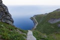 Descending concrete steps on Reinebringen trail, offering a breathtaking view of the North Sea and coastal road on Lofoten Island