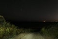 Descent of a dirt road from a hill to the night sea. Sea coast at night.