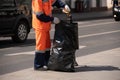 The janitor takes the trash out of the street urn and puts it in a big black bag Royalty Free Stock Photo