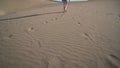 Desert landscape - female legs against the background of sand blown by the wind on a sunny day. Slow mo, wide angle