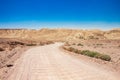 Desert landscape sand valley curved dirt trail foreground and stone rocky mountain range horizon background summer time hot Royalty Free Stock Photo