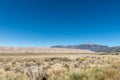 Desert landscape of shrub grassland, sand dunes, and mountains under a clear blue sky Royalty Free Stock Photo