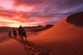 Desert landscape at sunset with camels, pink skies, sun setting over horizon, sand dunes stretch Royalty Free Stock Photo