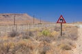 Desert landscape view of a sharp left turn sign on a dirt road i