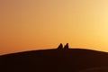 Desert nomads on the crest of a barchan at sunset Royalty Free Stock Photo