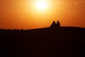 Desert nomads on the crest of a barchan at sunset