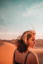 Desert portrait: A woman's hair dances with the wind, embodying untamed beauty and a sense of enchantment amidst the barren