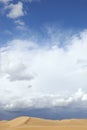 Desert sand dunes with cloudy blue sky. Royalty Free Stock Photo