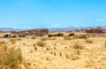 Desert sand landscape with mountains in the background and road with bus, near Al Ula, Saudi Arabia